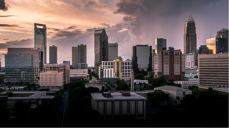 City skyline at sunset with tall buildings and dramatic cloudy sky.